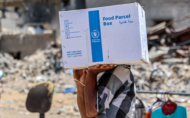 Illustrative: A man carries a humanitarian aid package provided by the United Nations Relief and Works Agency for Palestine Refugees (UNRWA) in central Gaza City on August 27, 2024. (Omar AL-QATTAA / AFP) Illustrative: A man carries a humanitarian aid package provided by the United Nations Relief and Works Agency for Palestine Refugees (UNRWA) in central Gaza City on August 27, 2024. (Omar AL-QATTAA / AFP)