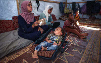 Palestinian boy Abdel Rahman Abu al-Jedian who contracted polio a month ago, sleeps surrounded by family members in their displacement tent in Deir al-Balah in the central Gaza Strip on August 27, 2024. (Eyad Baba/AFP)