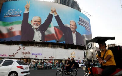 Vehicles drive past a huge banner showing slain Hamas leader Ismail Haniyeh (left) joining hands with Iranian President Masoud Pezeshkian, in a square in downtown Tehran, Iran, August 5, 2024. (AP Photo/Vahid Salemi)