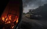 A Ukrainian tank passes by a burning car near the Russian-Ukrainian border, Sumy region, Ukraine, Wednesday, August 14, 2024. (AP Photo/Evgeniy Maloletka)