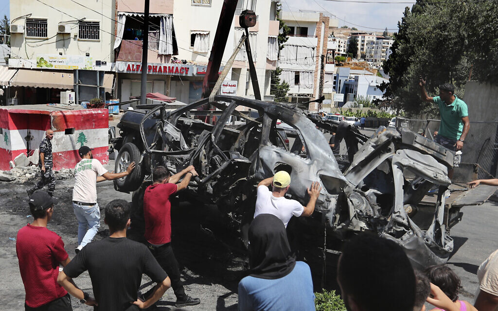 Workers use a crane to remove a car that was hit by an Israeli strike in the southern Lebanon port city of Sidon, August 21, 2024. (AP Photo/Mohammed Zaatari)