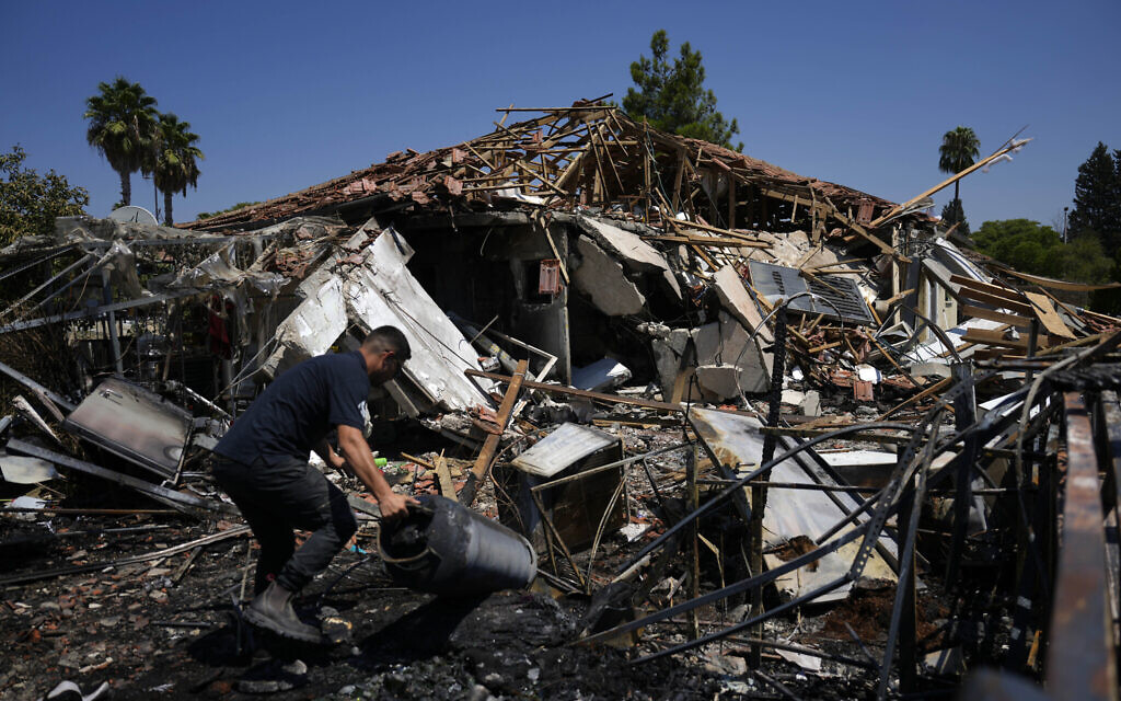 A man works next to a home destroyed by rockets fired by Hezbollah in Katzrin on the Golan Heights, August 21, 2024.(AP Photo/Ariel Schalit)