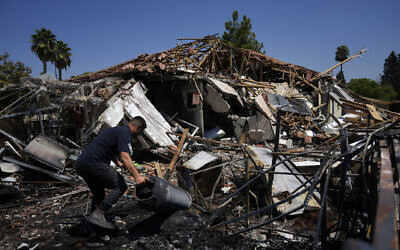 A man works next to a home destroyed by rockets fired by Hezbollah in Katzrin on the Golan Heights, August 21, 2024.(AP Photo/Ariel Schalit)