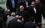 Iranian President Masoud Pezeshkian, center, is greeted by lawmakers while leaving the parliament after his speech during the debate on his proposed ministers, at the Majlis in Tehran, August 21, 2024.  (AP Photo/Vahid Salemi)