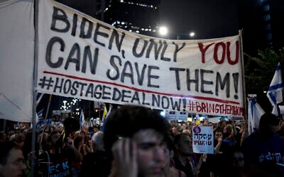 Activists carry a message for US President Joe Biden as relatives of hostages held by Hamas in the Gaza Strip and their supporters call for their immediate release and to protest against Prime Minister Benjamin Netanyahu's government, in Tel Aviv on August 24, 2024. (AP Photo/Maya Alleruzzo)