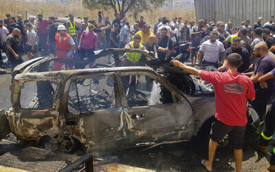 Civil Defense workers and citizens inspect the remains of a burned car that was hit by an alleged Israeli strike near the port city of Sidon, Lebanon, Monday, Aug. 26, 2024. (AP/Mohammed Zaatari)