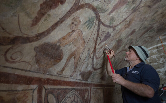 A worker touches up an ancient wall drawing of Greek goddess Demeter at an archeological tomb site in Ashkelon, Israel, on Tuesday August 27, 2024. (AP/Ohad Zwigenberg)