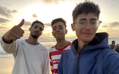 In this undated photo provided by Helmi Hirez, Mohamed (Medo) Halimy, left, and twin brothers Mohammed Hirez, center, and Helmi Hirez, right, stand on a beach in Gaza. (Helmi Hirez via AP)
