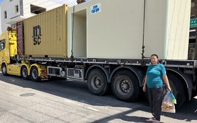Eeman Nasra stands by a bomb shelter being delivered to Mazra'a, August 8, 2024. (Diana Bletter/Times of Israel)