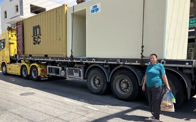 Eeman Nasra stands by a bomb shelter being delivered to Mazra'a, August 8, 2024. (Diana Bletter/Times of Israel)