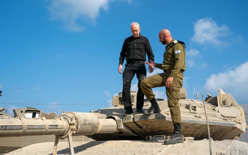 Defense Minister Yoav Gallant speaks with an officer on a tank at a military base, August 4, 2024. (Ariel Hermoni/Defense Ministry)