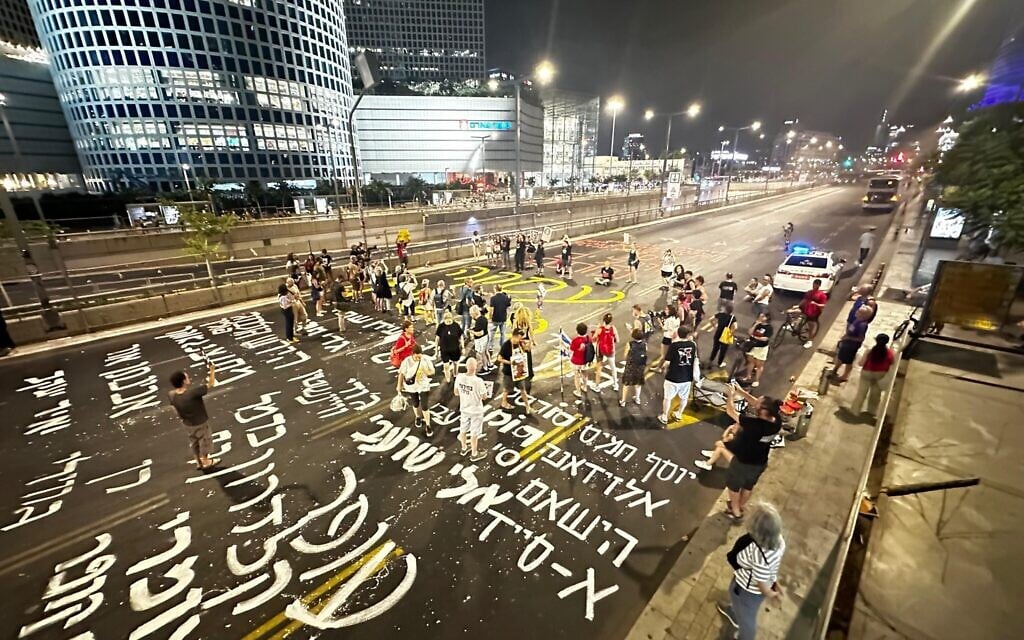 Protesters write the names of Hamas hostages on the ground on Begin Road in Tel Aviv amid calls for a hostage deal, August 20, 2024. (Oded Engel/Pro-Democracy Protest Movement)