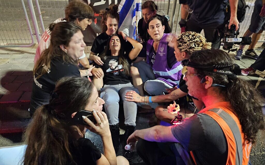 Natalie Zangauker, center, sister of hostage Matan Zangauker, is tended to by other protesters for a hostage deal after she was pushed on the road by mounted police and injured on Begin Road in Tel Aviv, August 31, 2024. (Zohar Bar-Yehuda/Pro-Democracy Protest Movement)