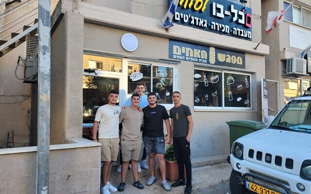 Teenagers hang out outside a computer store in Jish on August 5, 2024. (Canaan Lidor/Times of Israel)