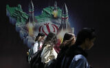 Iranian women without a mandatory headscarf, or hijab, walk past a banner showing missiles being launched from Iranian map in northern Tehran, Iran, April 19, 2024. (AP Photo/Vahid Salemi)