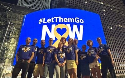 James Oppenheim (left), his wife and nine children stand in front of his 'Let Them Go Now' messaging billboard on Tel Aviv's Azrieli towers in April 2024 (Courtesy)