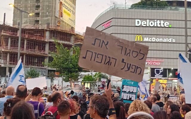 Protester Iftach Brill's sign reads 'shut down the corpse industry,' at a rally calling for a truce-hostage deal, on Tel Aviv's Begin Street, outside the IDF headquarters, September 4, 2024. (Noam Lehmann/Times of Israel)
