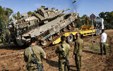 An Israeli tank rolls onto a trailer truck at a position along the border with the Gaza Strip on January 2, 2024. (Jack Guez/AFP)