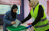 An election staff member assists a woman casting her ballot for parliamentary elections at a polling station at the al-Baqaa Palestinian refugee camp near the capital Amman on September 10, 2024. (Photo by Khalil MAZRAAWI / AFP)