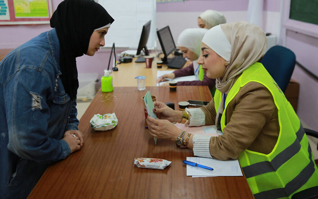 An election staff member assists a Jordanian woman who arrived to vote for parliamentary elections at a polling station at the al-Baqaa Palestinian refugee camp near the capital Amman on September 10, 2024. (Photo by Khalil MAZRAAWI / AFP)