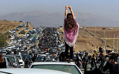 This UGC image posted on Twitter reportedly on October 26, 2022 shows an unveiled woman standing on top of a vehicle as thousands make their way towards Aichi cemetery in Saqez, Mahsa Amini's hometown in the western Iranian province of Kurdistan, to mark 40 days since her death in morality police custody. (UGC / AFP)