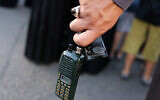 A man holds a walkie-talkie device after he removed the battery during the funeral of persons killed when hundreds of paging devices exploded in an alleged Israeli attack on Hezbollah across Lebanon the previous day, in Beirut's southern suburbs on September 18, 2024. (Anwar Amro/AFP)