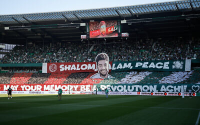 Banners reading 'Shalom, salam, peace' and showing the colors and symbol of the Hapoel Jerusalem club's fan group 'Brigade Malcha' are held by fans of SV Werder Bremen in memory of murdered Israeli-American hostage Hersh Goldberg-Polin, prior to the German first division Bundesliga soccer match between SV Werder Bremen and FC Bayern Munich in Bremen, northern Germany, September 21, 2024. (Axel Heimken/AFP)