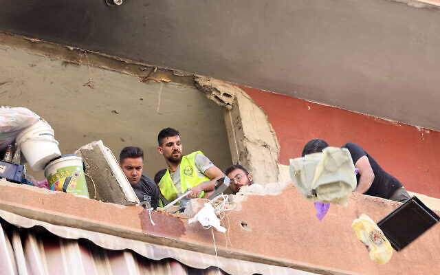 People remove the rubble in a residential building whose top two floors were hit by an Israeli strike on the head of Hezbollah's missile unit in the Ghobeiri area of Beirut's southern suburbs on September 24, 2024. (Photo by ANWAR AMRO / AFP)