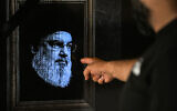 A man points to a television set displaying an image of Hezbollah leader Hassan Nasrallah with a black stripe for mourning during a broadcast from the private Lebanese station NBN in Beirut on September 28, 2024. (JOSEPH EID / AFP)