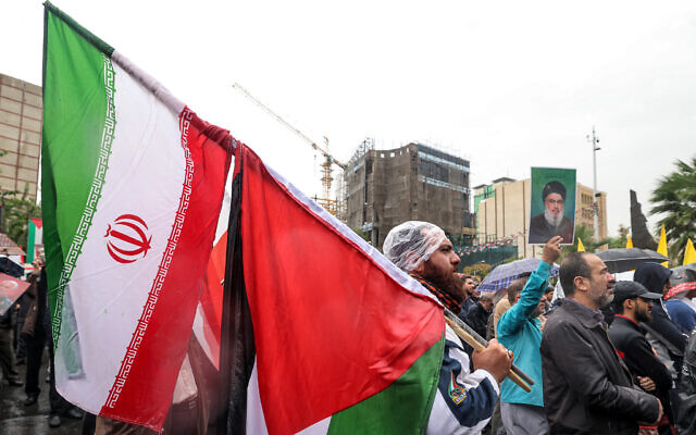 A man stands in the rain with an Iranian and a Palestinian flag during an anti-Israel protest in Tehran's Palestine Square on September 28, 2024. (ATTA KENARE / AFP)