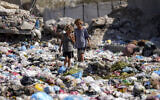 Displaced kids sort through trash at a street in Deir al-Balah, central Gaza Strip, Thursday, August 29, 2024. (AP Photo/Abdel Kareem Hana)
