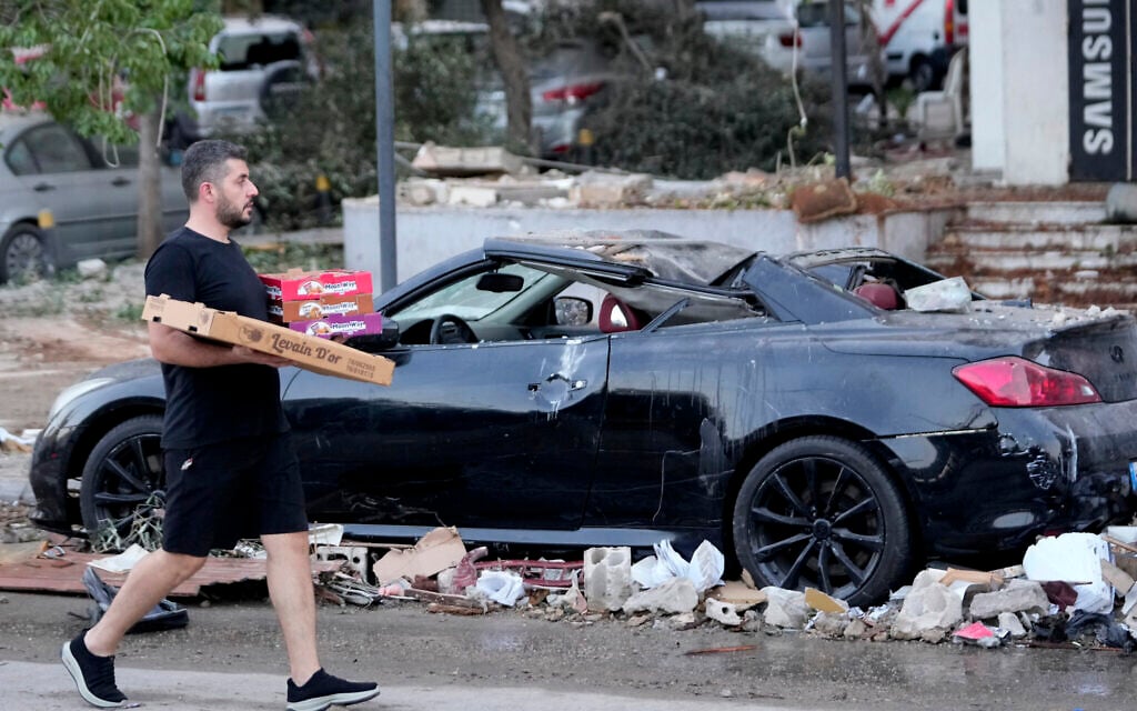 A man passes by a damaged car where an Israeli airstrike on a Hezbollah target hit a nearby building in Beirut, Lebanon, September 30, 2024. (AP Photo/Hussein Malla)