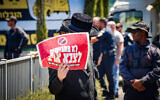 An ultra-Orthodox Jew protesting against the drafting of Haredim to the Israeli army holds a sign reading, 'We won't draft to an enemy army,' outside the IDF Recruitment Center at Tel Hashomer, in central Israel, September 2, 2024. (Avshalom Sassoni/Flash90)