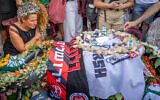 Friends and family attend the funeral of  slain hostage Hersh Goldberg-Polin at Har HaMenuchot cemetery in Jerusalem, September 2, 2024. By the grave of the slain hostage is draped the banner of the Hapoel Jerusalem soccer team. (Yonatan Sindel/Flash90)