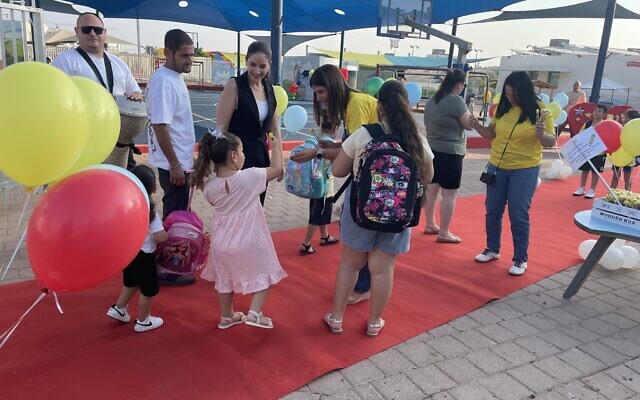 Idit Dayan (center, wearing yellow), the principal of the Gil Rabin School in Sderot, southern Israel, welcomes children back for the new school year, on September 1, 2024. (Sue Surkes/Times of Israel)