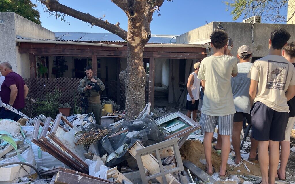 Neighbors gather in front of a Kibbutz Sa'ar house that suffered a direct hit from a Hezbollah rocket attack on September 25, 2024. (Diana Bletter/The Times of Israel) Neighbors gather in front of a Kibbutz Sa'ar house that suffered a direct hit from a Hezbollah rocket attack on September 25, 2024. (Diana Bletter/The Times of Israel)