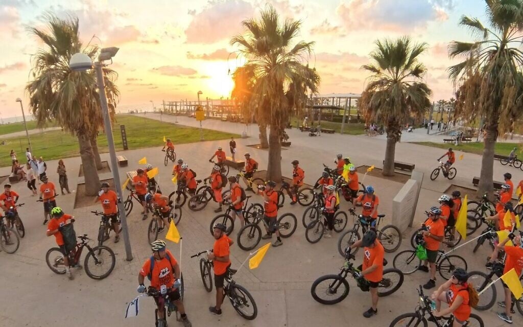 Cyclists wear orange T-shirts as they take part in a demonstration in honor of the Bibas family, held hostage by Hamas since October 7, in Tel Aviv, September 7, 2024. (Pro-Democracy Movement/Sharon Ben-Porath)
