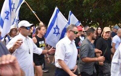 Protesters surround MK Yuli Edelstein as he walks to synagogue in Herzliya the day after three women were arrested for placing hostage flyers in the house of worship, September 14, 2024 (Yair Palti/Pro-Democracy Protest groups)