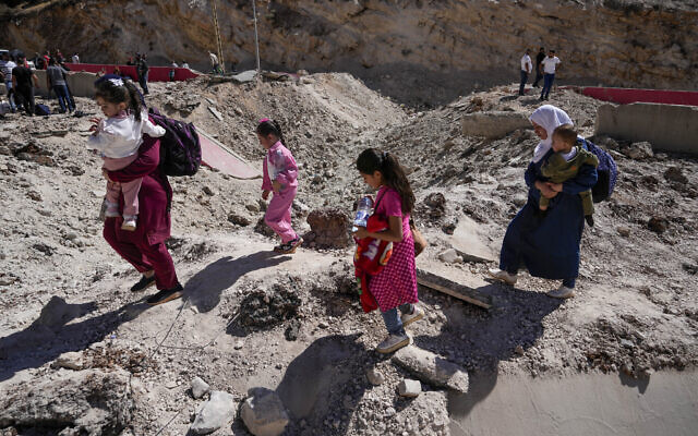 People carry their luggage as they cross into Syria on foot, through a crater caused by Israeli airstrikes aiming to block the Beirut-Damascus highway at the Masnaa crossing, in the eastern Beqaa Valley, Lebanon, Saturday, Oct. 5, 2024. (AP/Hassan Ammar) People carry their luggage as they cross into Syria on foot, through a crater caused by Israeli airstrikes aiming to block the Beirut-Damascus highway at the Masnaa crossing, in the eastern Beqaa Valley, Lebanon, Saturday, Oct. 5, 2024. (AP/Hassan Ammar)