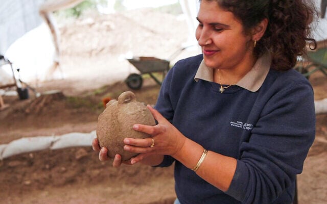 Archaeologist Maayan Hemed examines one of the ancient vessels, at the IAA excavation near Beit Shemesh, in a photo released on October 29, 2024. (Emil Aladjem/IAA)