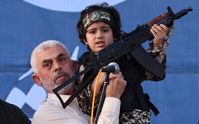 Hamas leader Yahya Sinwar holds the child of an Al-Qassam Brigades fighter with a Kalashnikov rifle in his hand during a rally in Gaza City on May 24, 2021. (Emmanuel Dunand/AFP)