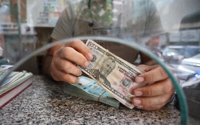 Illustrative: A money changer counts notes at his shop in the Lebanese capital Beirut on September 22, 2022. (Anwar Amro/AFP)