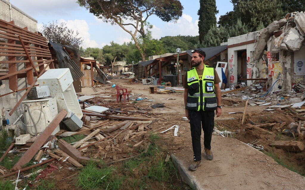 A volunteer from the Zaka body retrieval service walks past the debris of homes destroyed in the October 7 Hamas attack on Kibbutz Kfar Aza, November 14, 2023. (Gil Cohen-Magen / AFP)