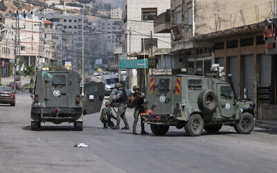 Israeli forces take position near their vehicles during a raid at the Balata refugee camp, east of Nablus, in the West Bank on October 1, 2024. (JAAFAR ASHTIYEH / AFP)