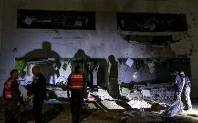 Members of Israel's Home Front Command and police forces inspect a crater left by an exploded projectile at a heavily damaged school building on October 1, 2024, after Iran launched a barrage of missiles at Israel (Menahem KAHANA / AFP)