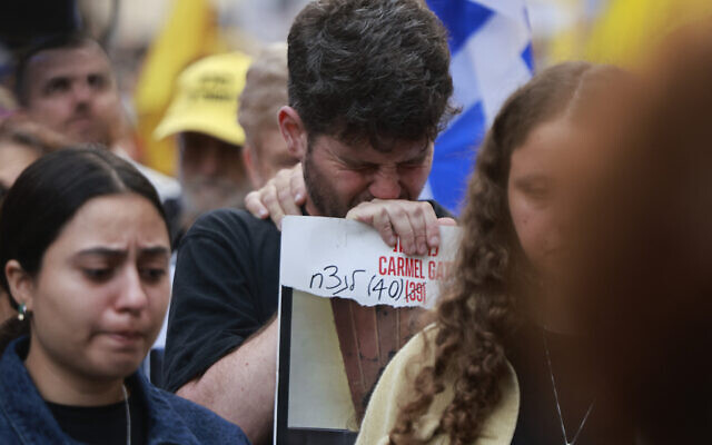 A man cries as he holds a photo of slain hostage Carmel Gat, taken by Hamas terrorists on October 7 and killed in Gaza 11 months later, during a protest on the terror onslaught's anniversary calling for the hostages' release, in front of Prime Minister Benjamin Netanyahu's residence in Jerusalem, October 7, 2024. (Menahem Kahana / AFP)