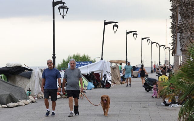 Lebanese men walk with a dog past tents where displaced people have been sleeping on Beirut's seaside promenade of Ain al-Mreisseh, on October 7, 2024. (Anwar AMRO / AFP) Lebanese men walk with a dog past tents where displaced people have been sleeping on Beirut's seaside promenade of Ain al-Mreisseh, on October 7, 2024. (Anwar AMRO / AFP)