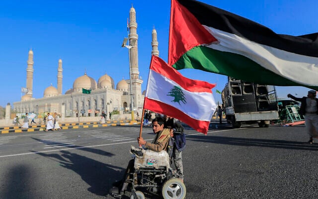 A Yemeni man using a wheelchair lifts flags of Lebanon and Palestine during a demonstration in support of Palestinians on the first anniversary of the October 7th Hamas massacre, in the Houthi-controlled capital Sanaa on October 7, 2024. (Photo by Mohammed HUWAIS / AFP) A Yemeni man using a wheelchair lifts flags of Lebanon and Palestine during a demonstration in support of Palestinians on the first anniversary of the October 7th Hamas massacre, in the Houthi-controlled capital Sanaa on October 7, 2024. (Photo by Mohammed HUWAIS / AFP)