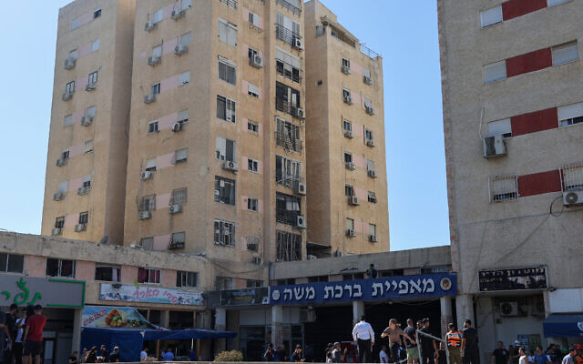 People gather near a building which was hit with a rocket fired from Lebanon, in Kiryat Yam near the northern city of Haifa on October 8, 2024 (Jack GUEZ / AFP)