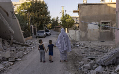 A woman and her two children walk along a street heavily damaged by Israeli airstrikes in Baalbek, Lebanon, October 9, 2024. (Fabio Bucciarelli / AFP)